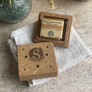 Boite en liège ouverte avec un savon dedans, le tout posé sur une pierre de travertin