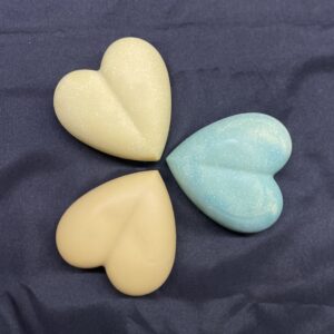 3 savon en forme de coeur vue de haut, sur une nappe noire