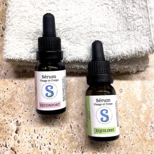 2 flacons de sérums l'un blanc et rose, l'autre blanc et vert